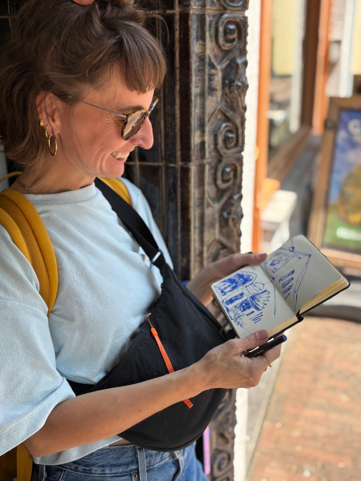 Malu  holding a notebook with drawings outdoors