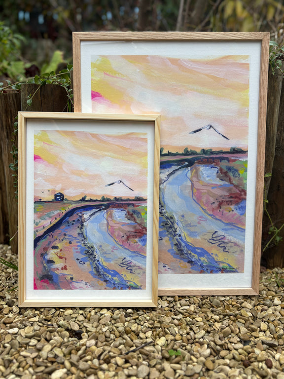 Two framed paintings of a landscape with a river and mountains on a pebble surface.