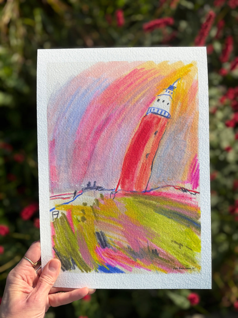 Colorful drawing of a lighthouse held by a hand with a blurred natural background