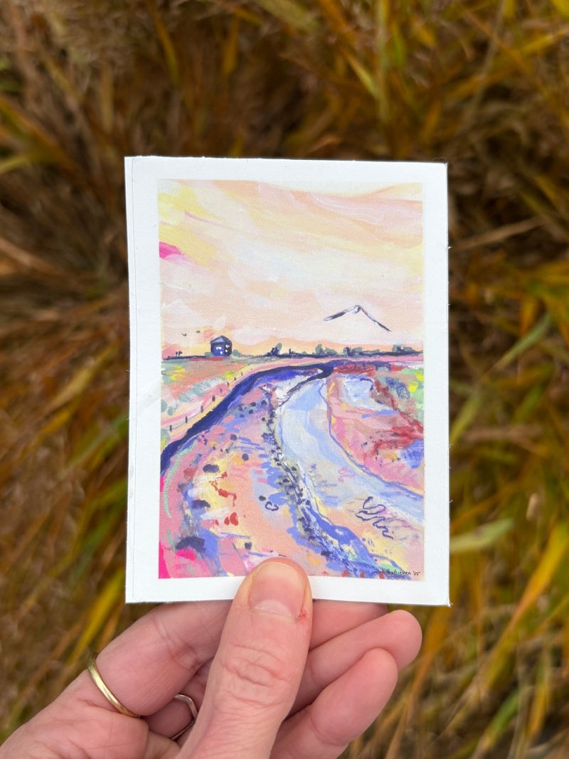 Hand holding vinyl sticker with a colorful landscape and a bird 